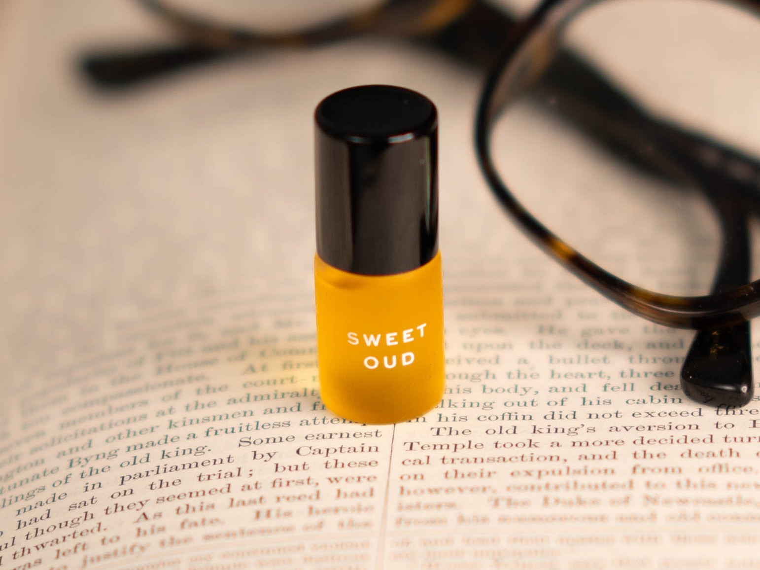 Oud rollerball on an open book beside reading glasses