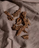 Agarwood oud chips on grey linen in warm light