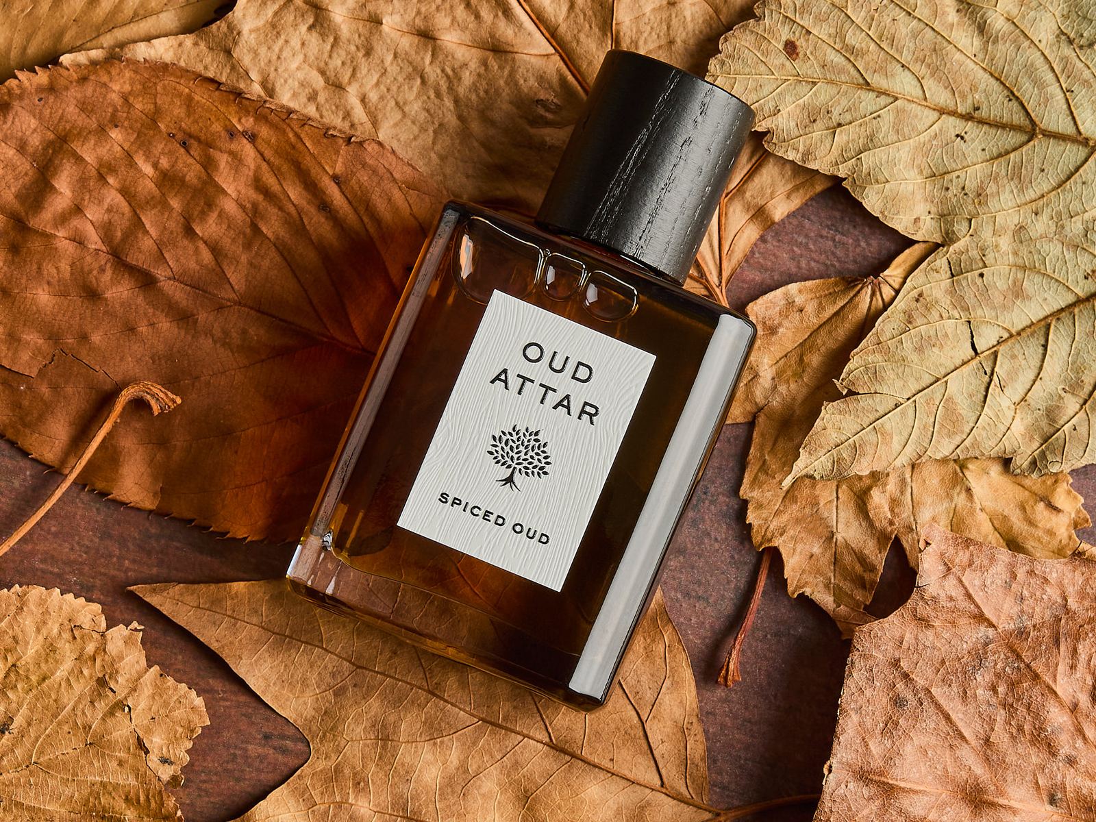 An Oud Attar bottle lying in a bed of dry autumn leaves