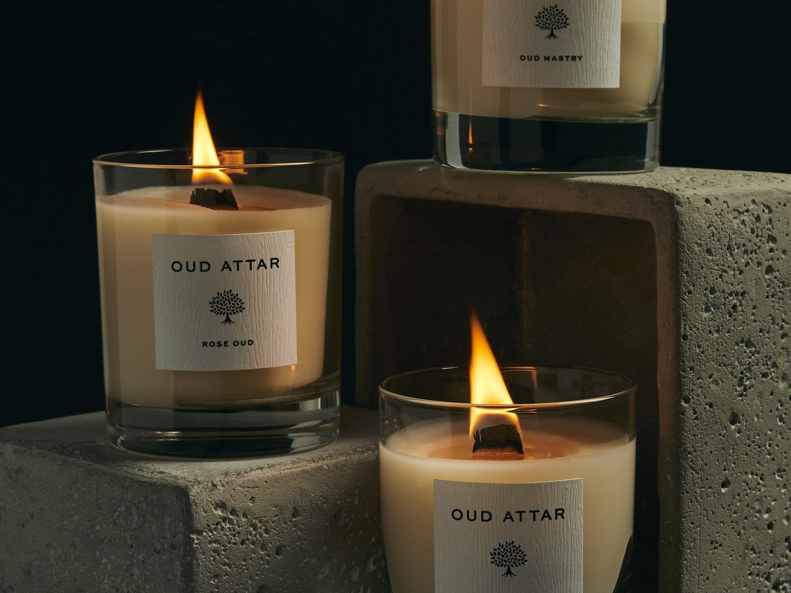 Three lit Oud Attar candles on stone blocks