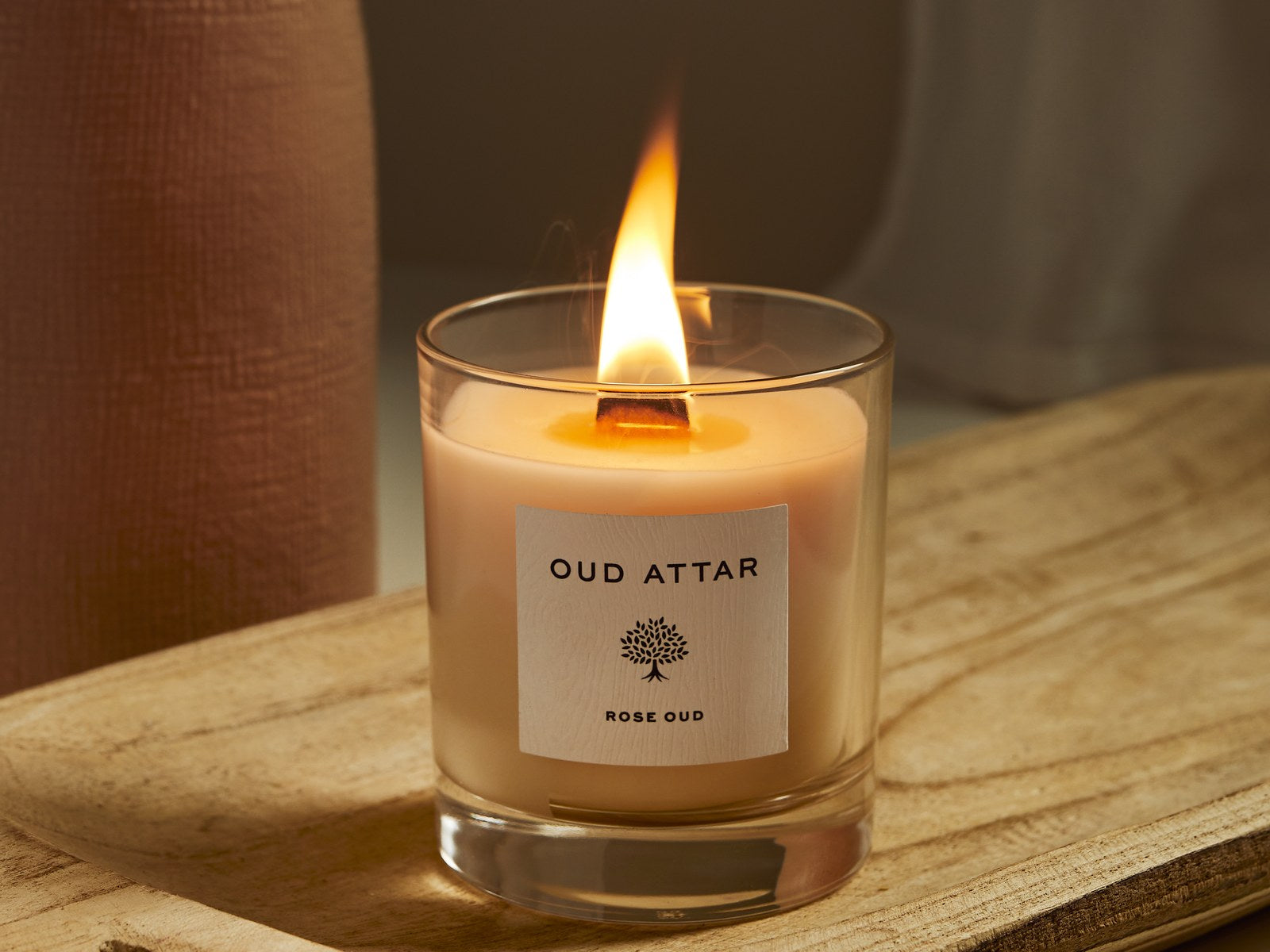Lit Oud Attar candle on a wooden board