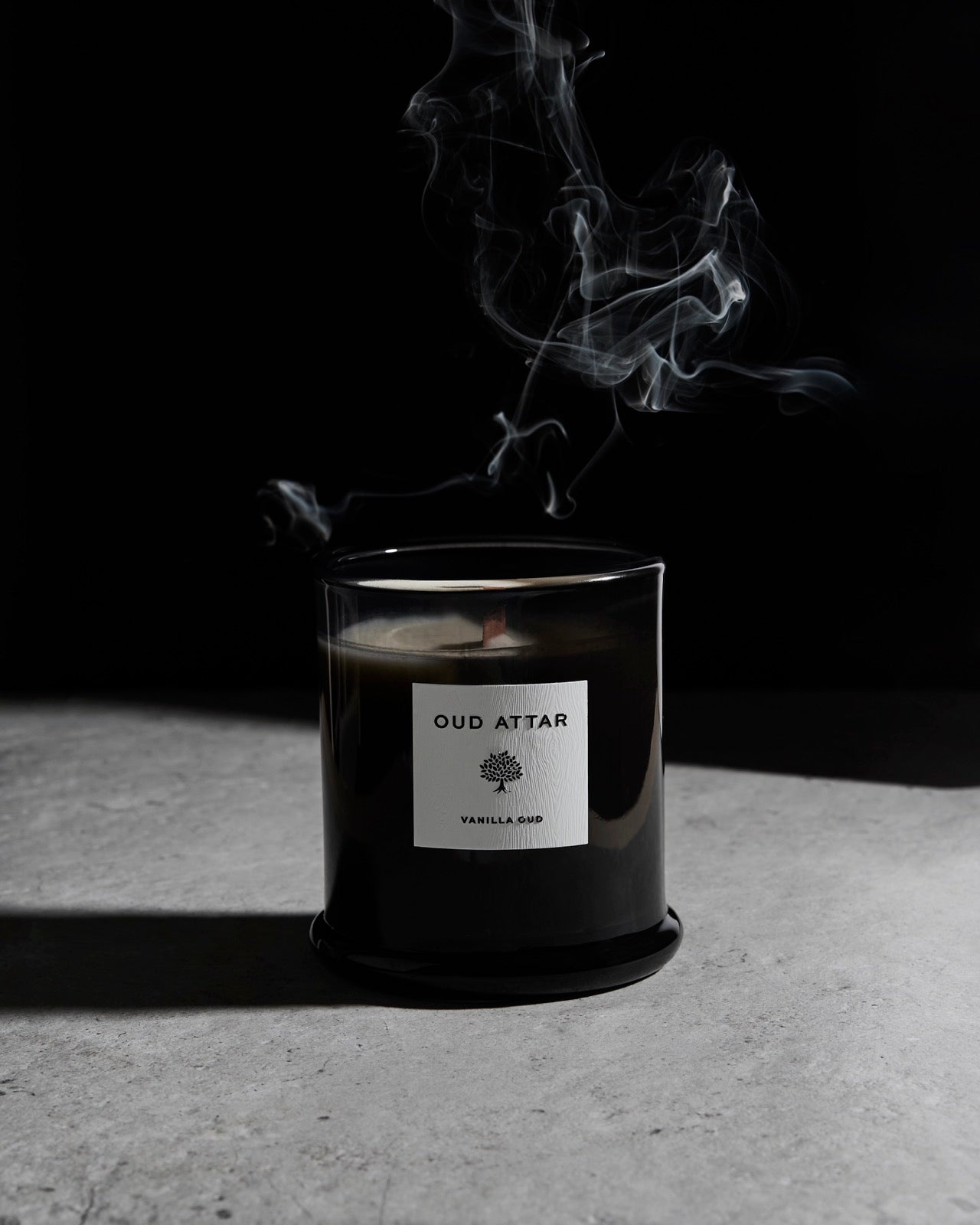 Vanilla Oud candle with smoke wisps on a dark backdrop