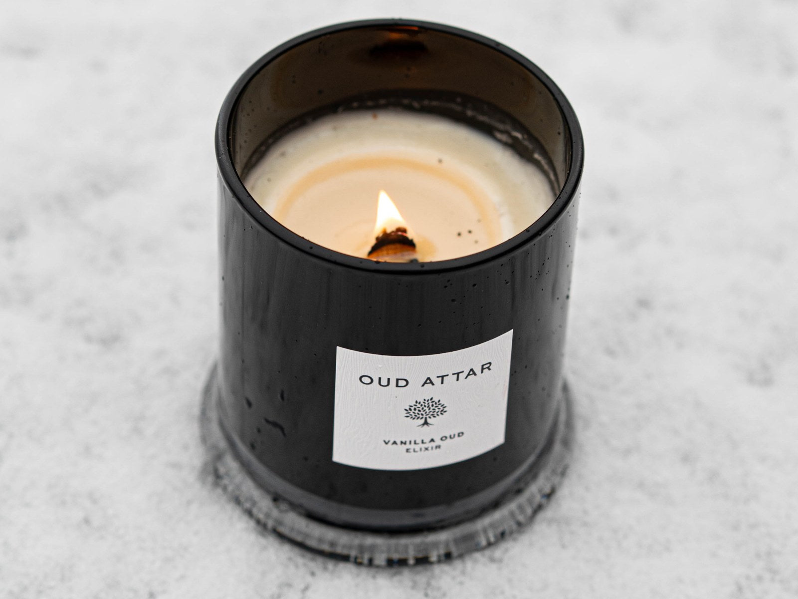 Lit black Oud Attar candle in the snow